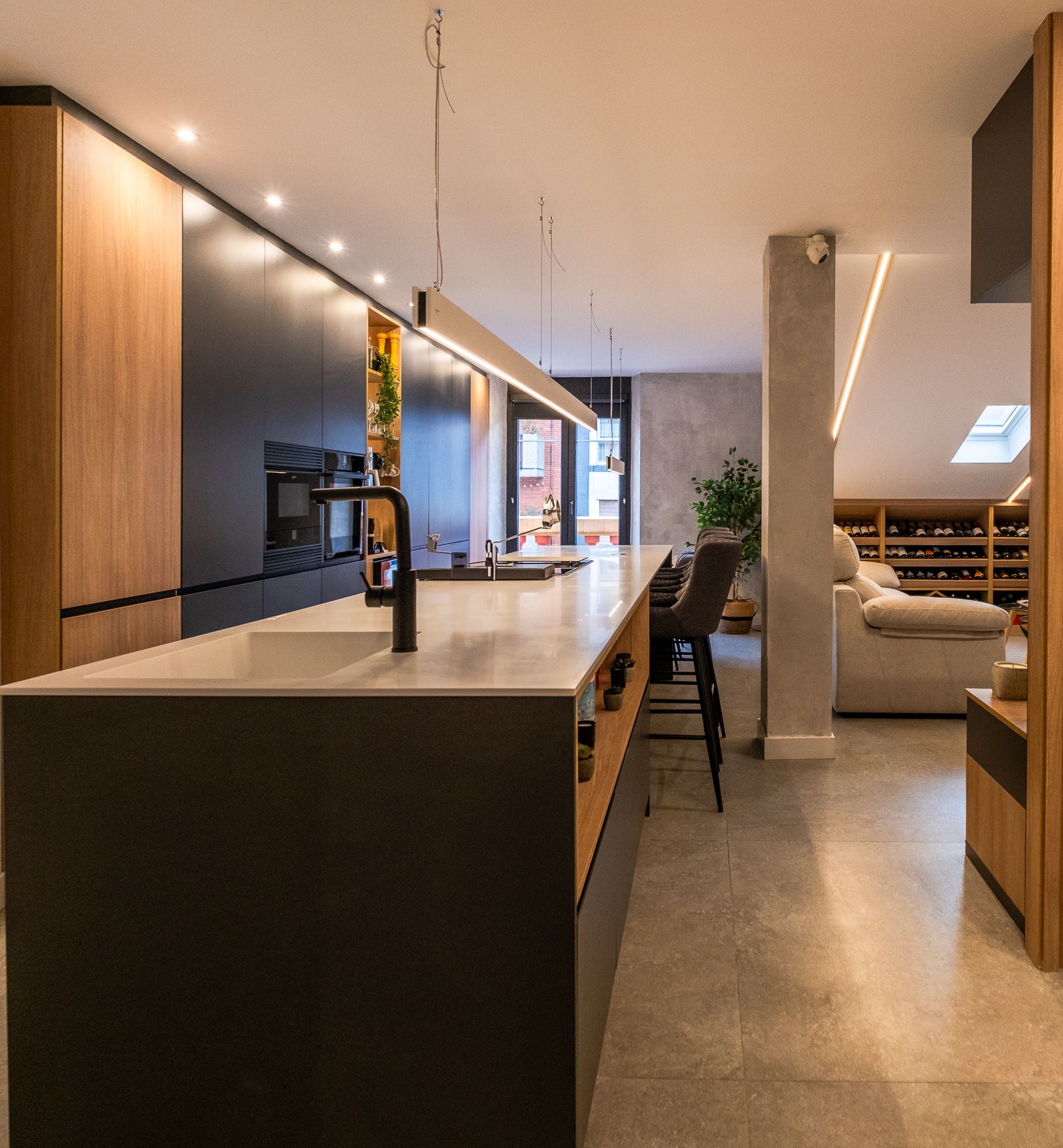 Cocina lineal con isla en negro mate y frentes de madera