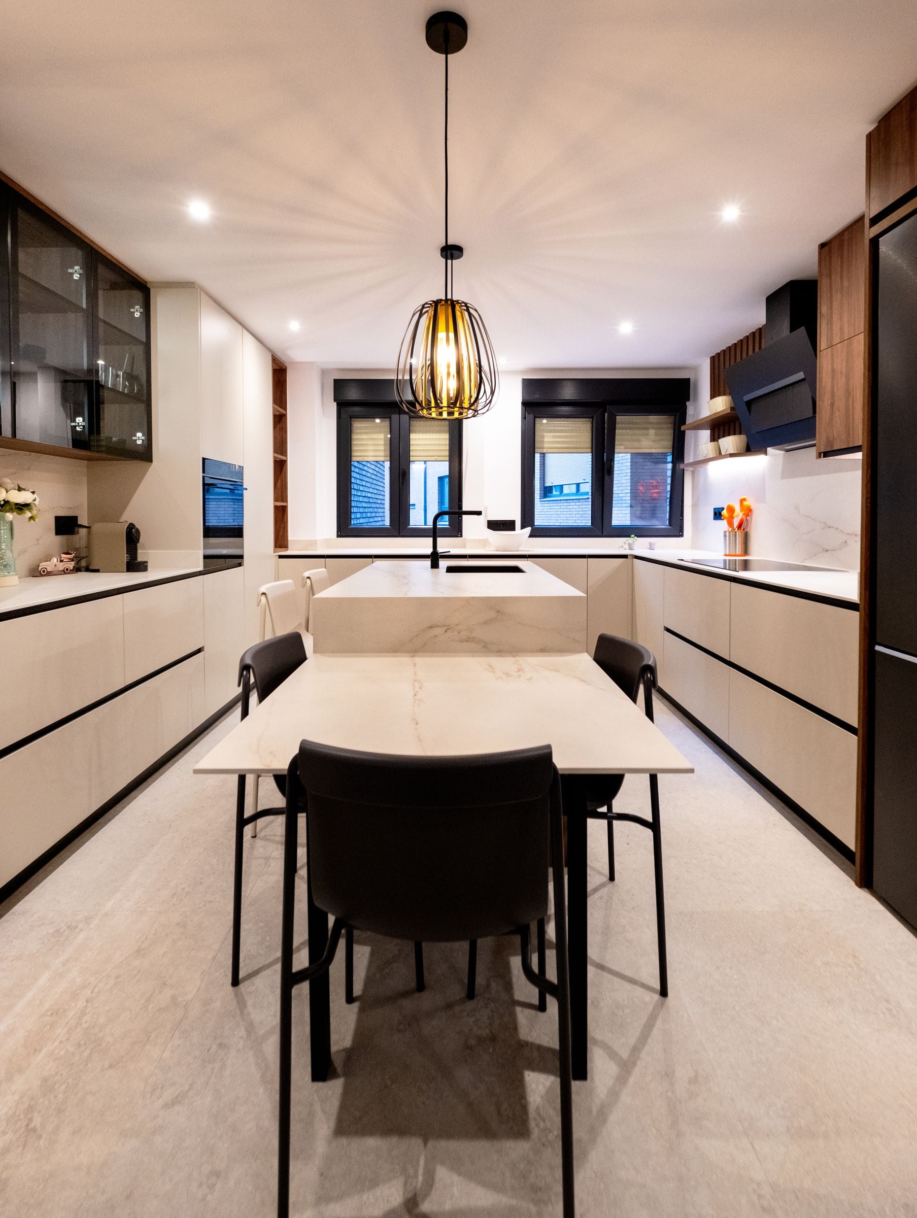 Cocina en tono arena con isla, frentes sin tirador y columnas de nogal
